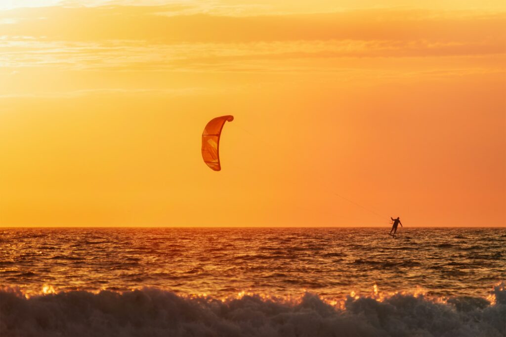 Kiteboarding kitesurfing kiteboarder kitesurfer kites silhouette in the ocean on sunset
